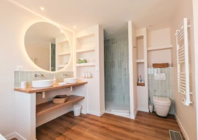 Salle de bain avec double vasques, douche italienne et wc.